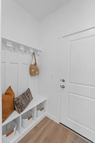 Built-in mudroom bench with cubby storage, integrated coat hooks, and wood-finish flooring
