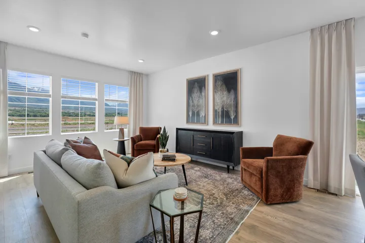 Spacious living area featuring expansive windows, recessed lighting, wood-finish flooring, and white walls