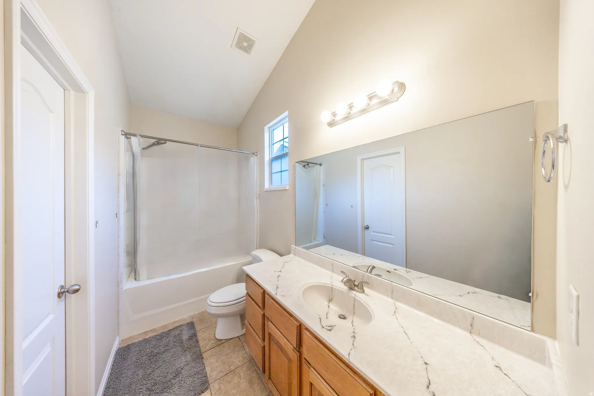 Single vanity with stone-finish countertop, integrated sink, and wood cabinetry