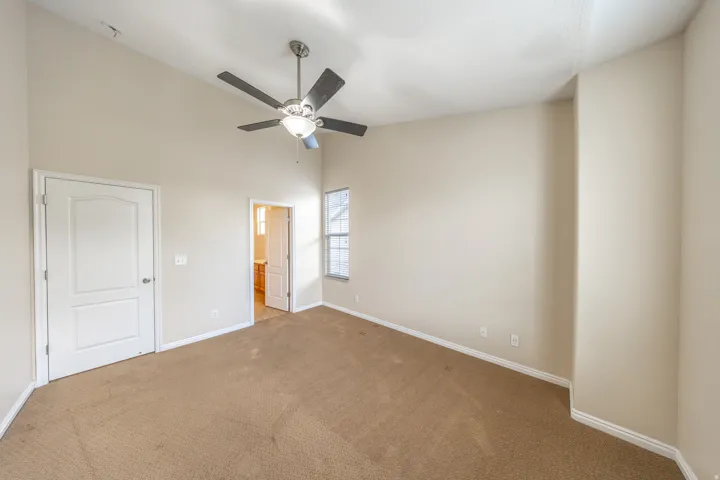 Vaulted ceiling with a ceiling fan, carpeted flooring, and a window with blinds
