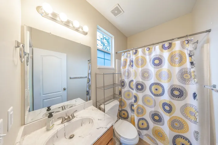 Single vanity with an integrated sink and brushed nickel faucet, large wall mirror, and overhead light fixture