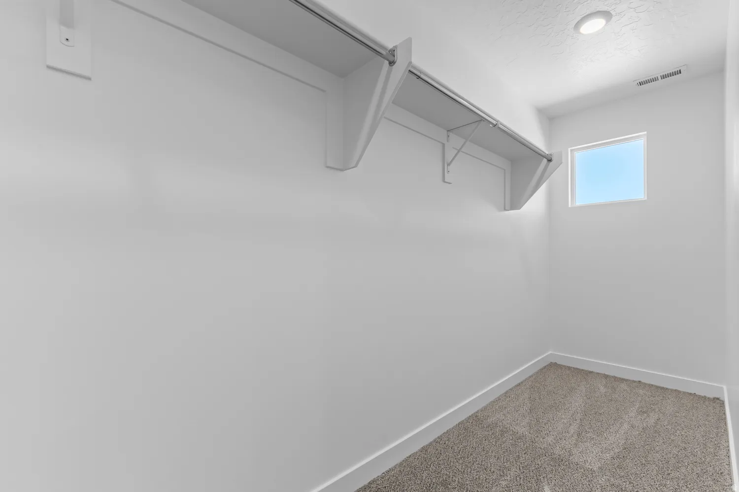 Integrated shelving and clothing rod, recessed ceiling lighting, single window, and light-toned carpet flooring