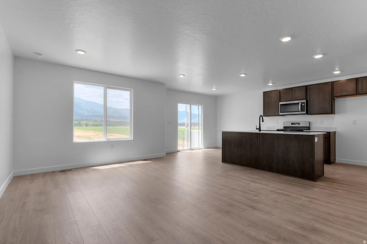 Open-concept living space featuring wood-finish flooring, recessed lighting, and white walls