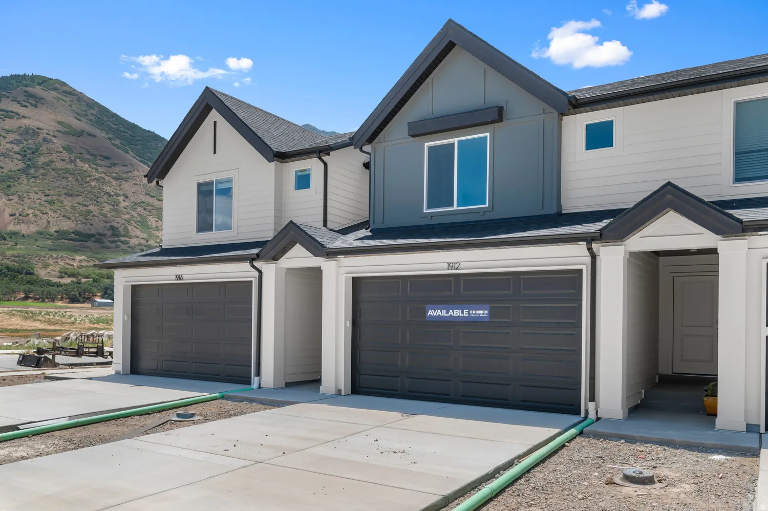 Contemporary townhome exterior with mixed siding, prominent gable roofs, and attached garages
