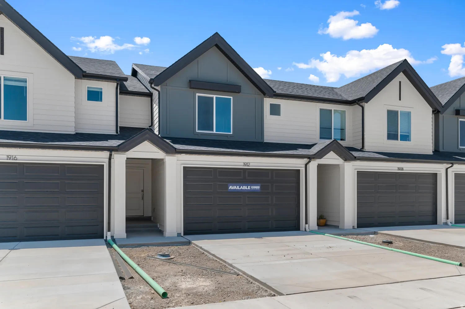 Contemporary townhome exterior featuring multi-toned siding, dark gray garage doors, and individual covered entryways