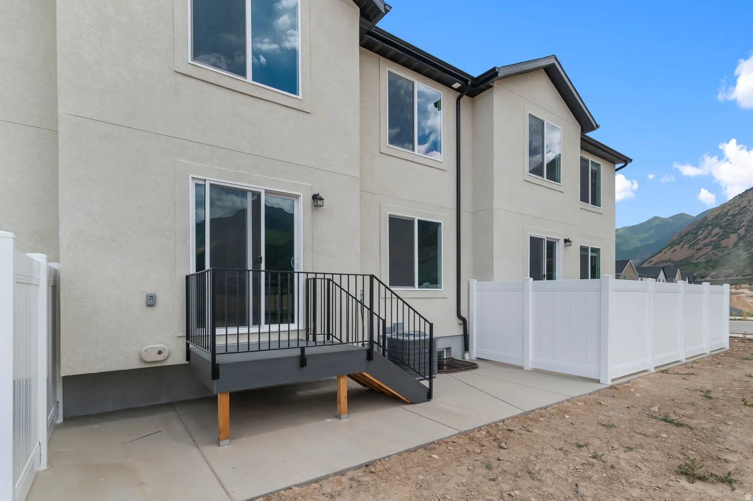 Exterior patio featuring a white vinyl fence, sliding glass door, and a private deck with black railings