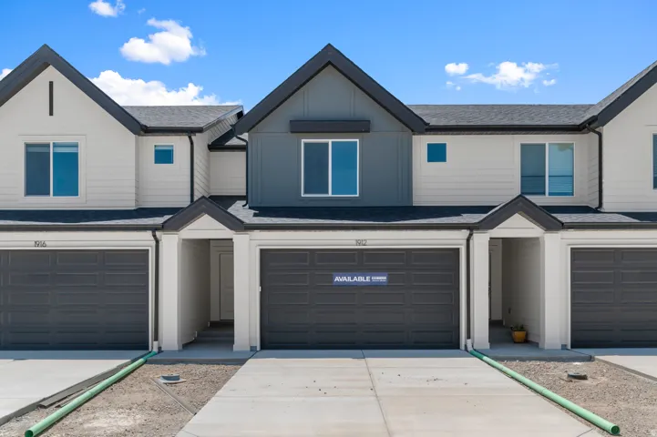Modern townhome exterior with contrasting siding, dark garage doors, and individual covered entryways