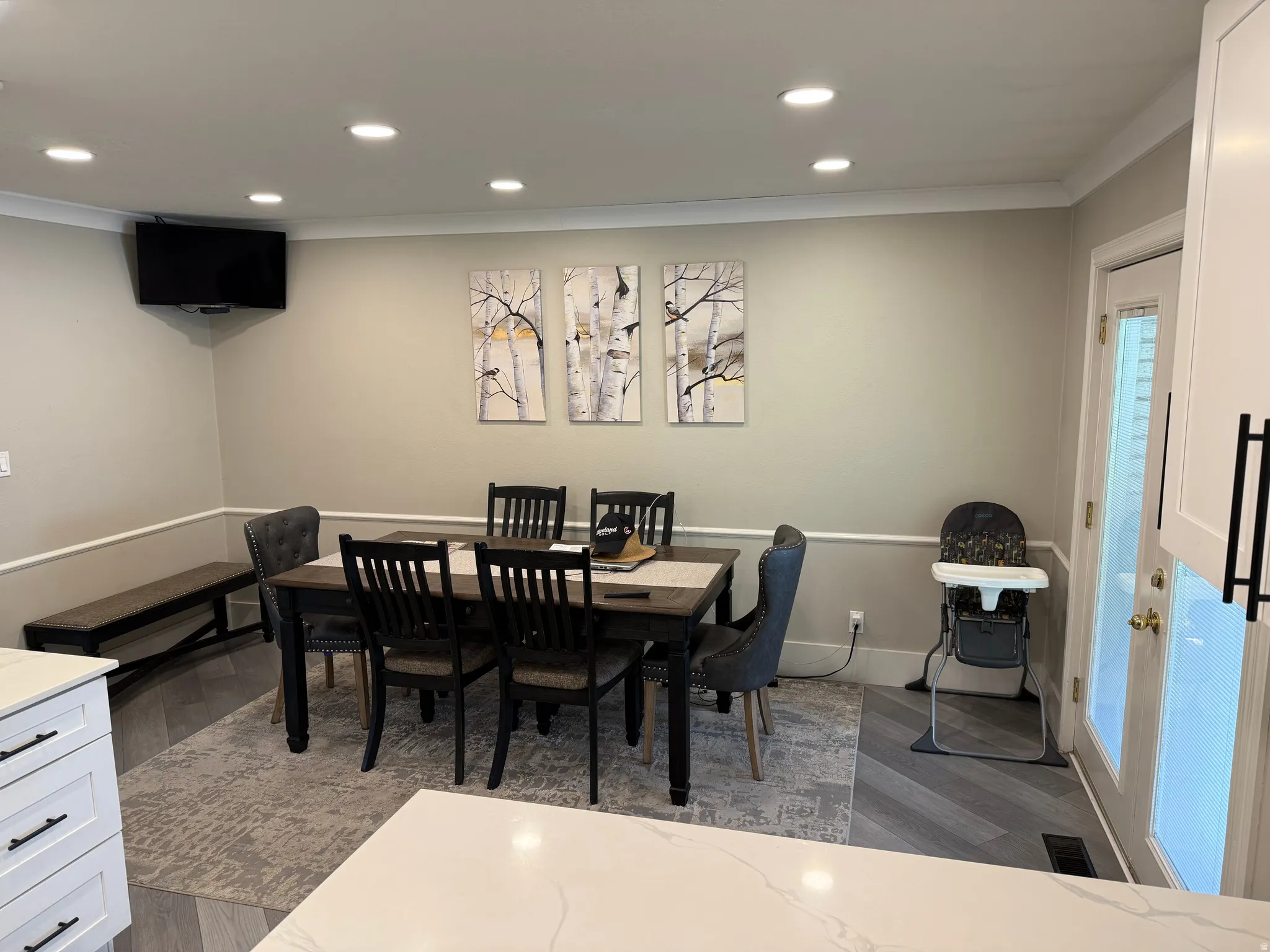 Recessed ceiling lighting, crown molding, chair rail molding, wood-finish flooring, and a built-in bench