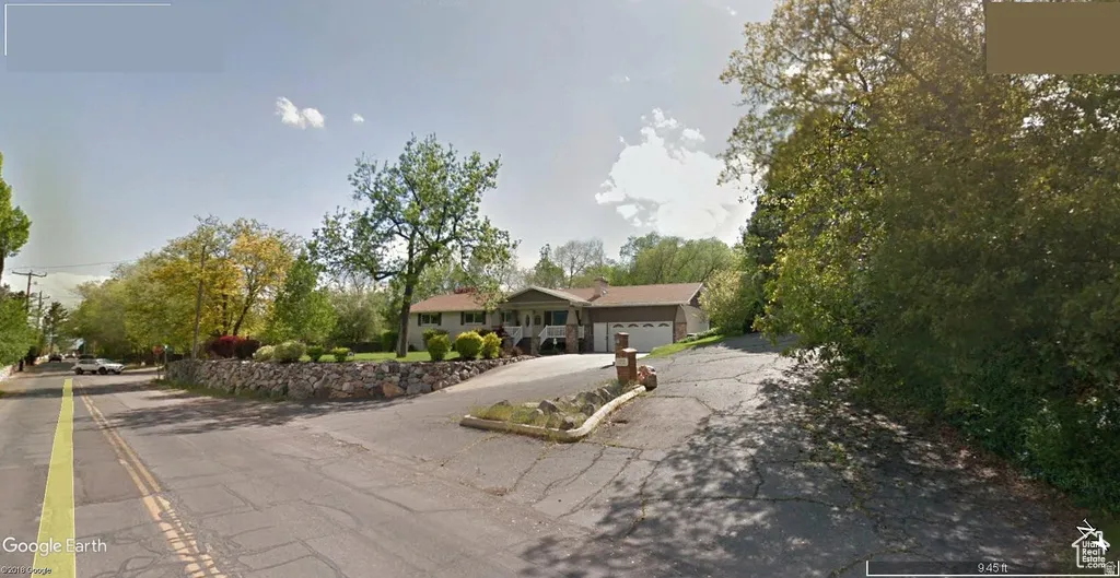 Ranch-style residence featuring a prominent front porch, an attached garage, and a stone retaining wall