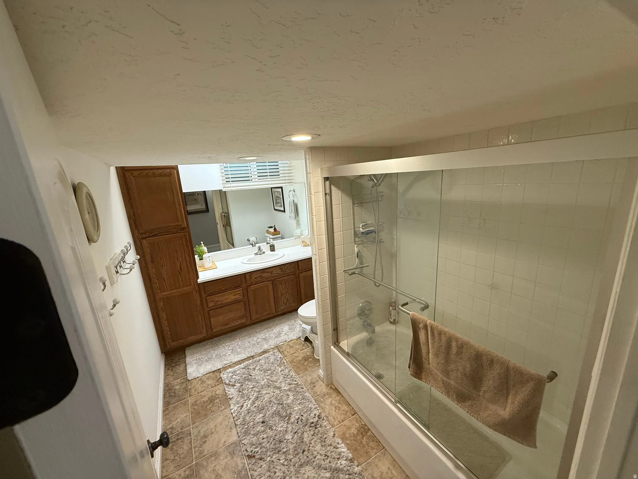 Vanity with wood-finish cabinetry, integrated sink, and white countertop