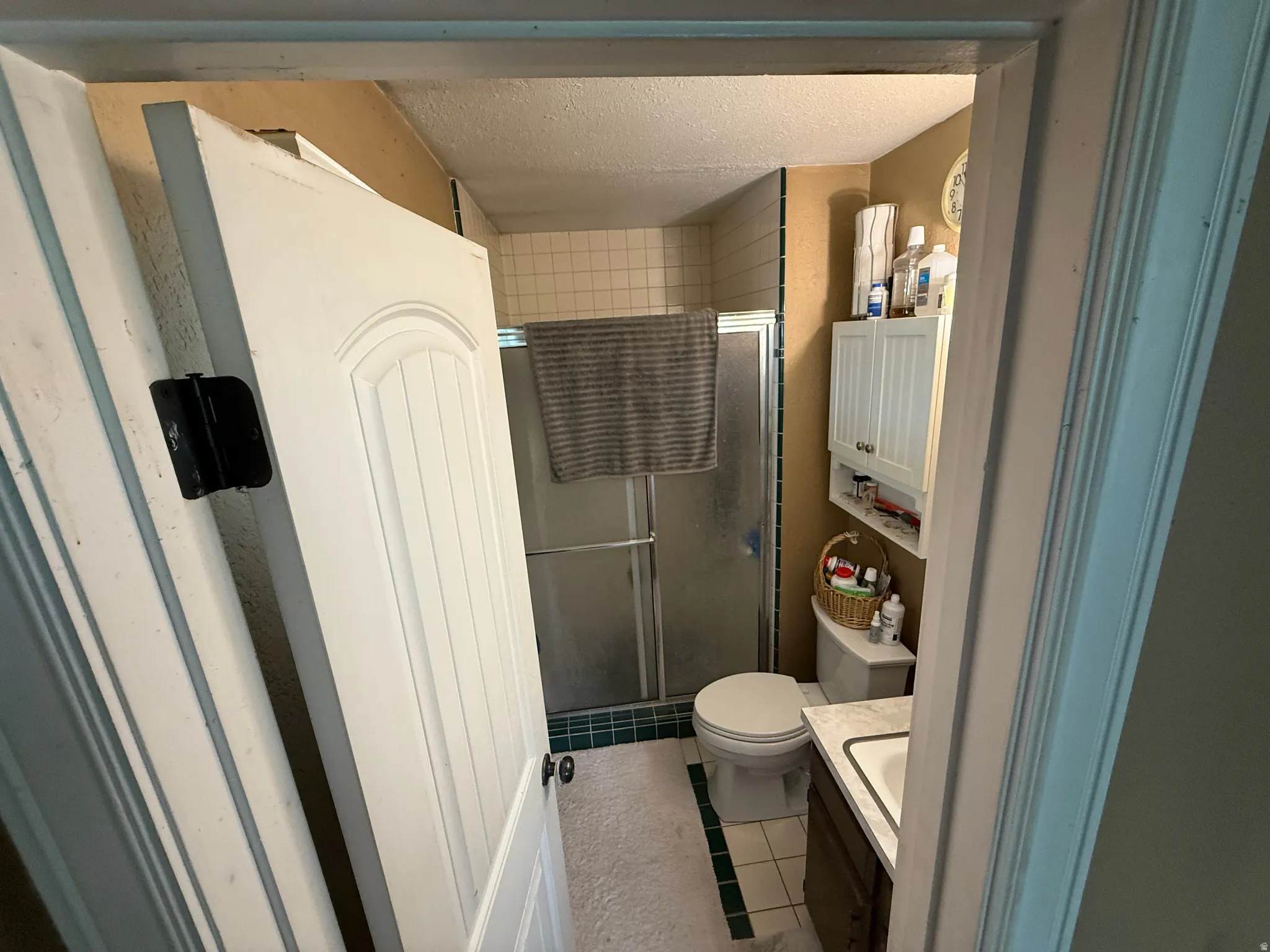 Shower enclosure with glass door, white tiled walls, and built-in medicine cabinet