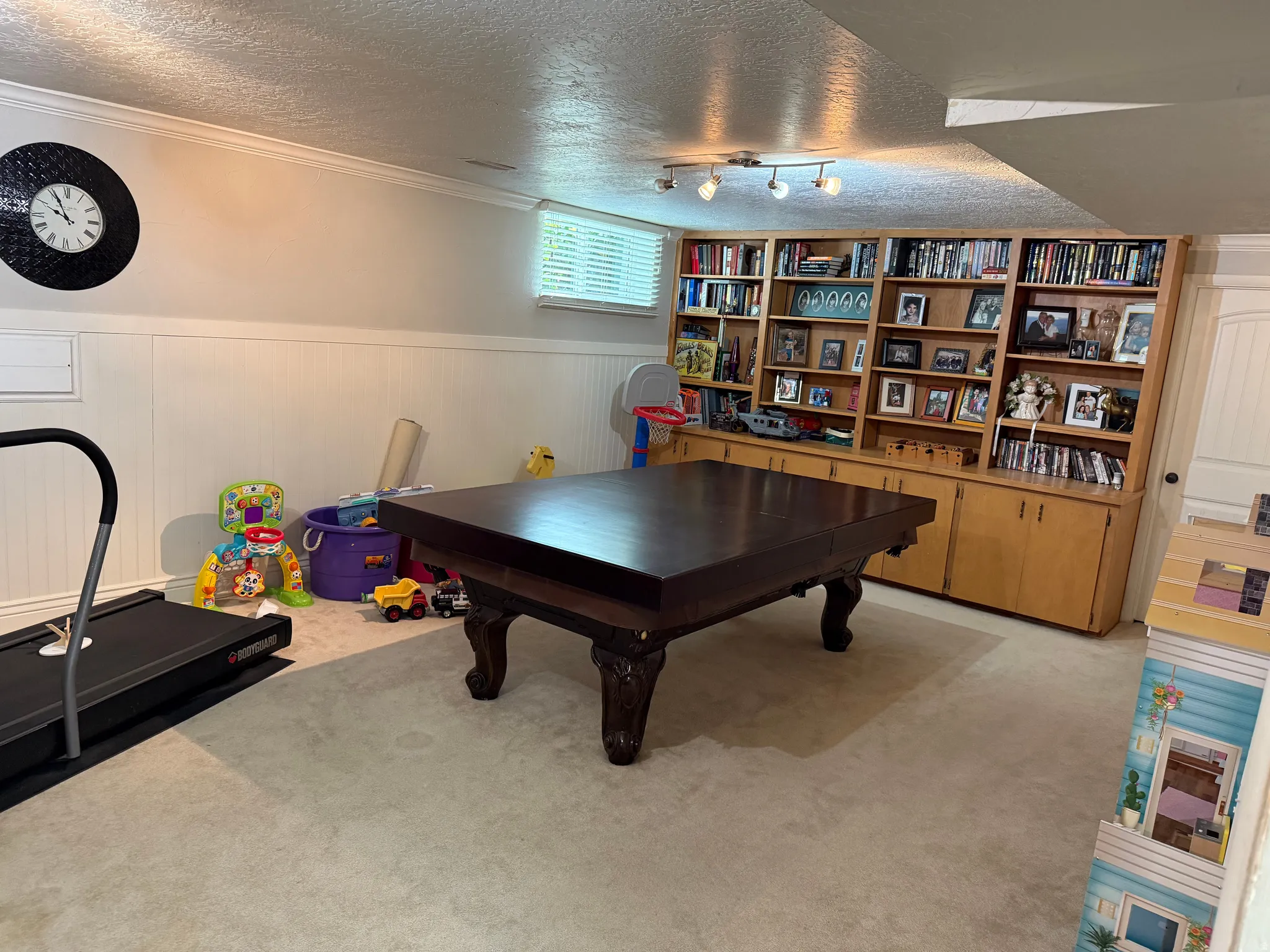 Built-in shelving with lower cabinetry, recessed window, wall paneling, and carpeted flooring