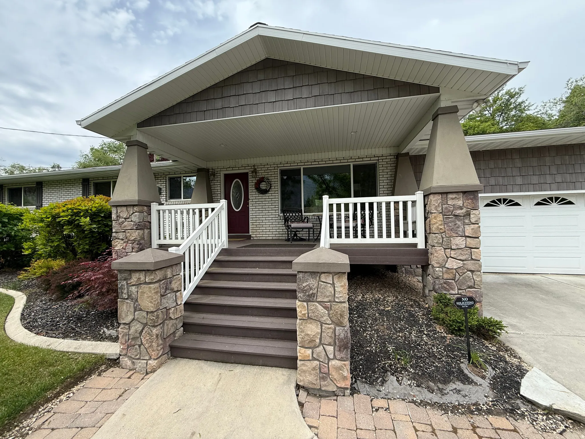Covered porch with stone-clad columns and composite decking
