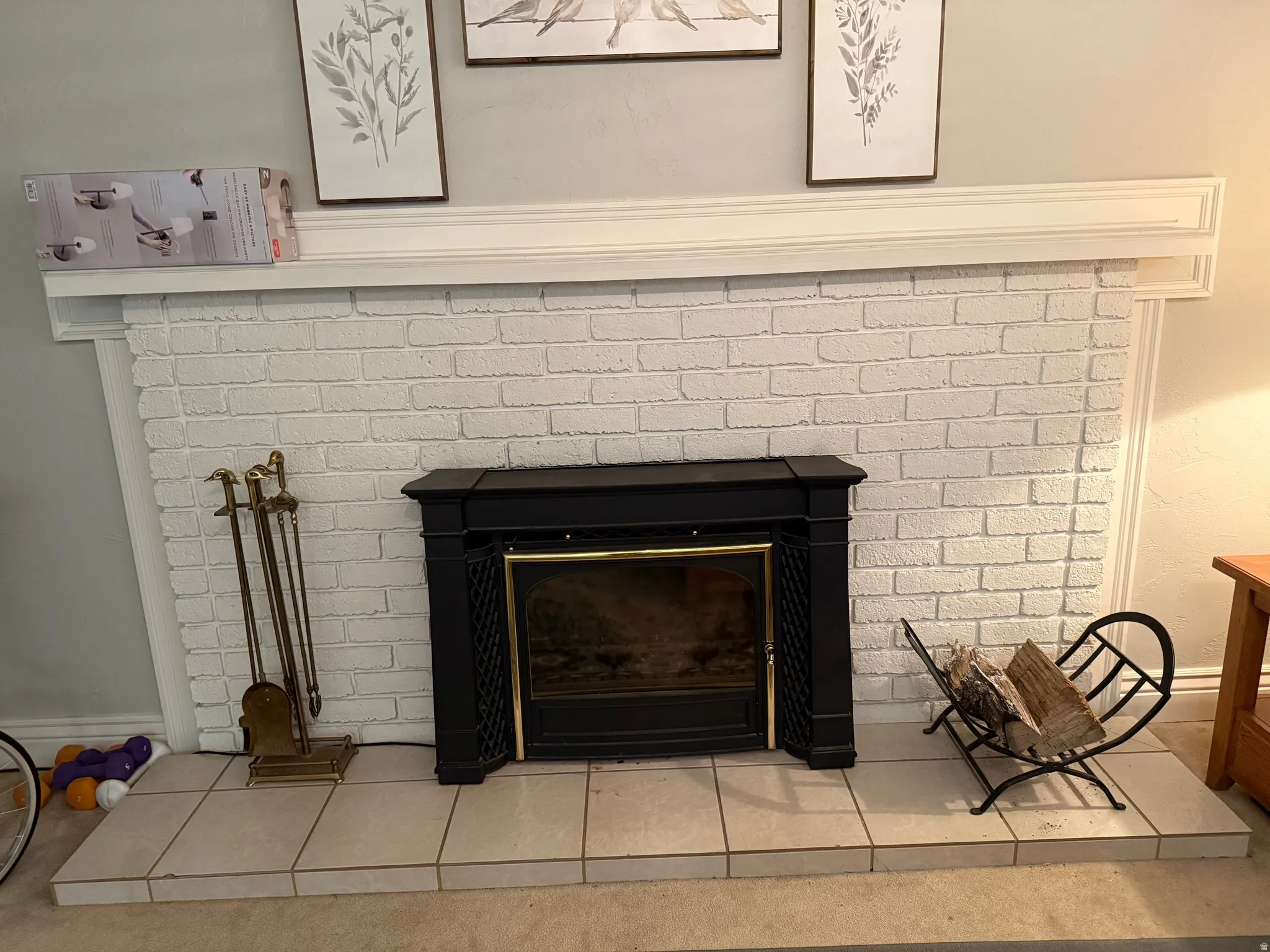 White painted brick fireplace with a detailed mantel, dark metal insert, and tiled hearth
