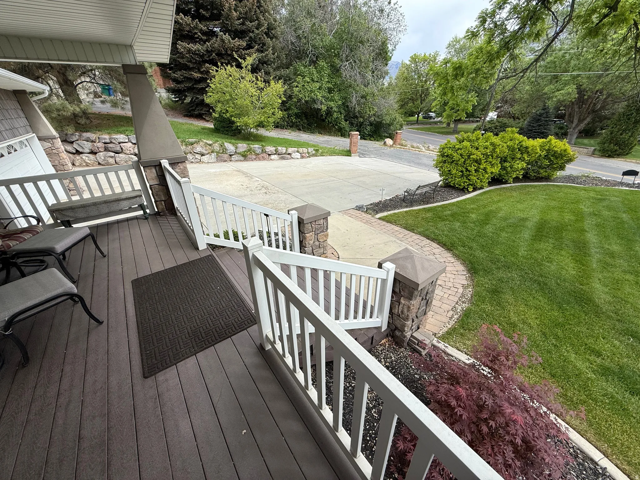 Front porch with composite decking, white railing, and stone-clad columns