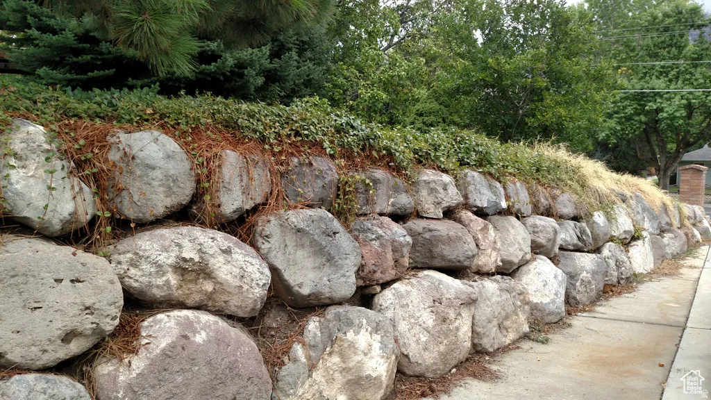 Stacked stone retaining wall with integrated plantings and mature trees