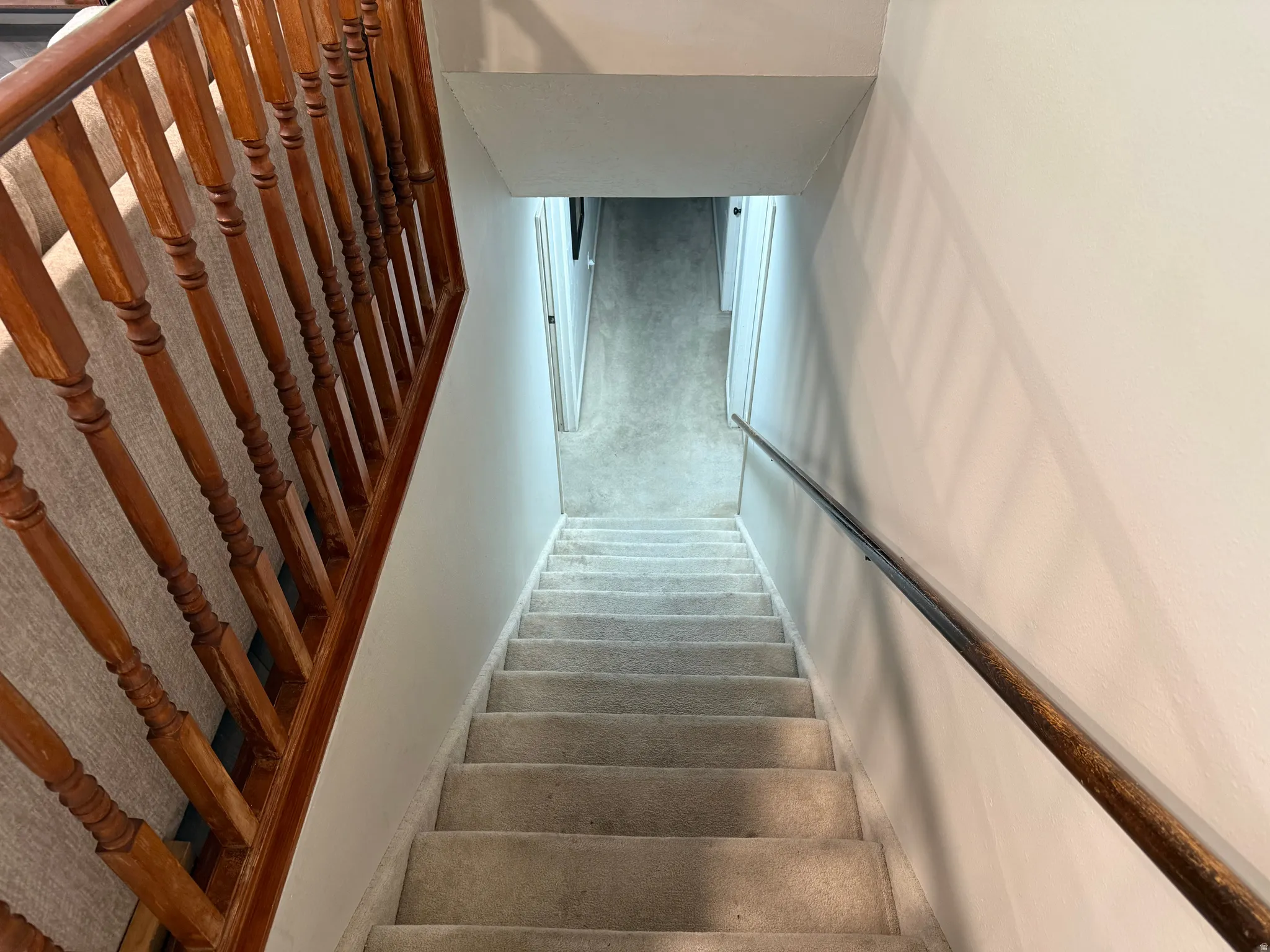 Carpeted stairway with a wooden banister and a wall-mounted handrail