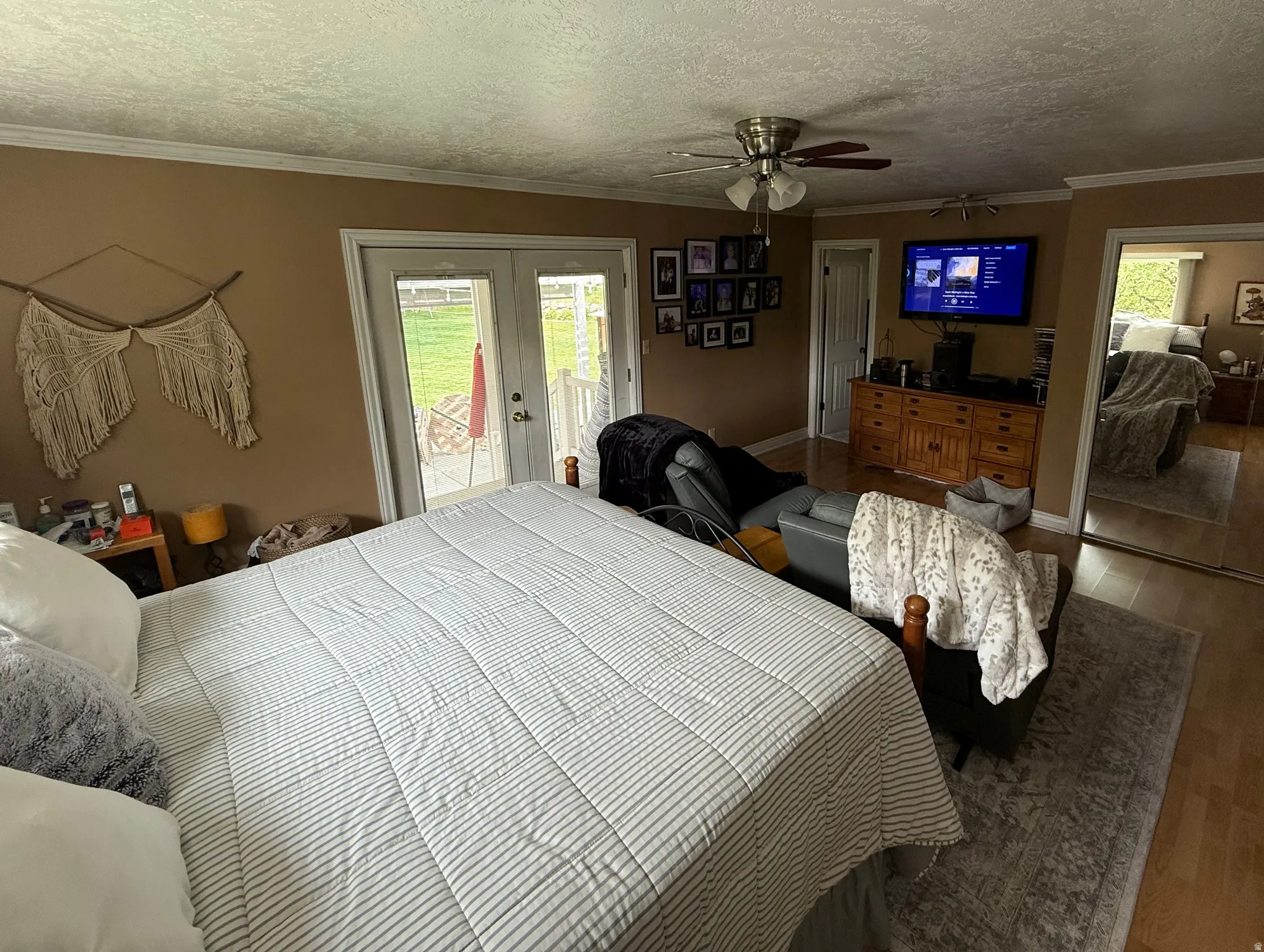 French doors leading to an exterior space, wood-finish flooring, ceiling fan with integrated lighting, and crown molding