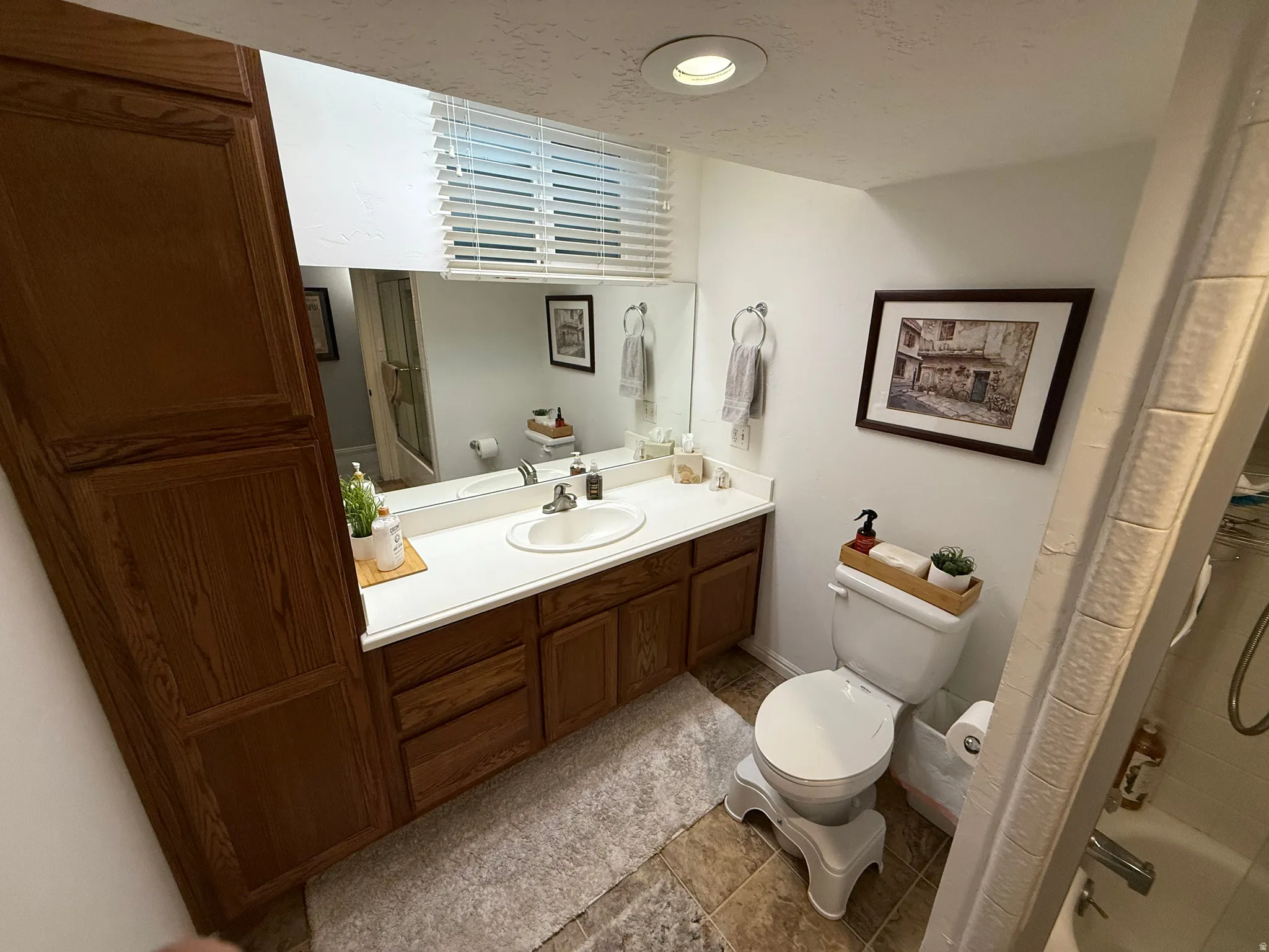 Built-in storage cabinetry, vanity with integrated sink, large vanity mirror, tile flooring, and recessed lighting