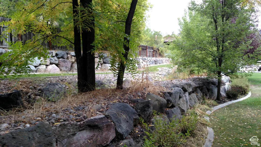 Terraced landscaping with a rock retaining wall, mature trees, and a sculpted lawn edge