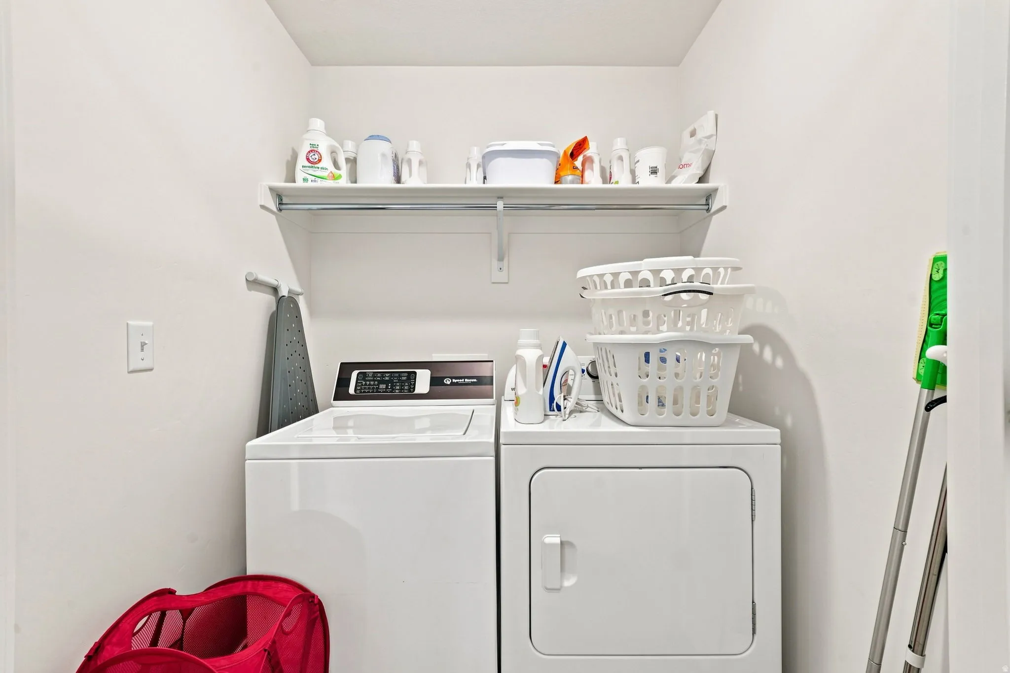 Dedicated laundry area featuring a white top-load washer, a white front-load dryer, and an overhead built-in shelving unit