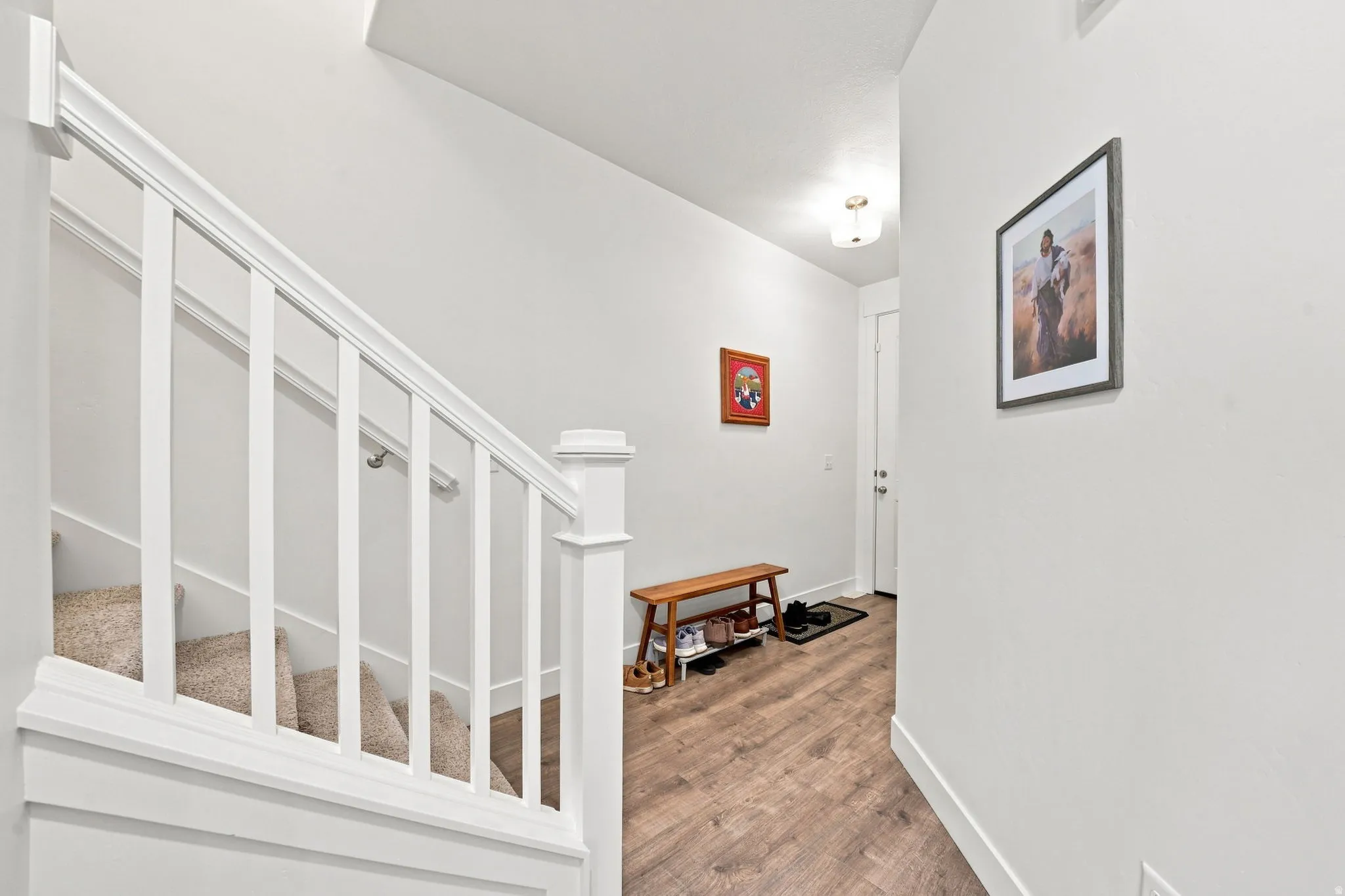 Carpeted staircase with white railings, wood-finish flooring, and a recessed ceiling light