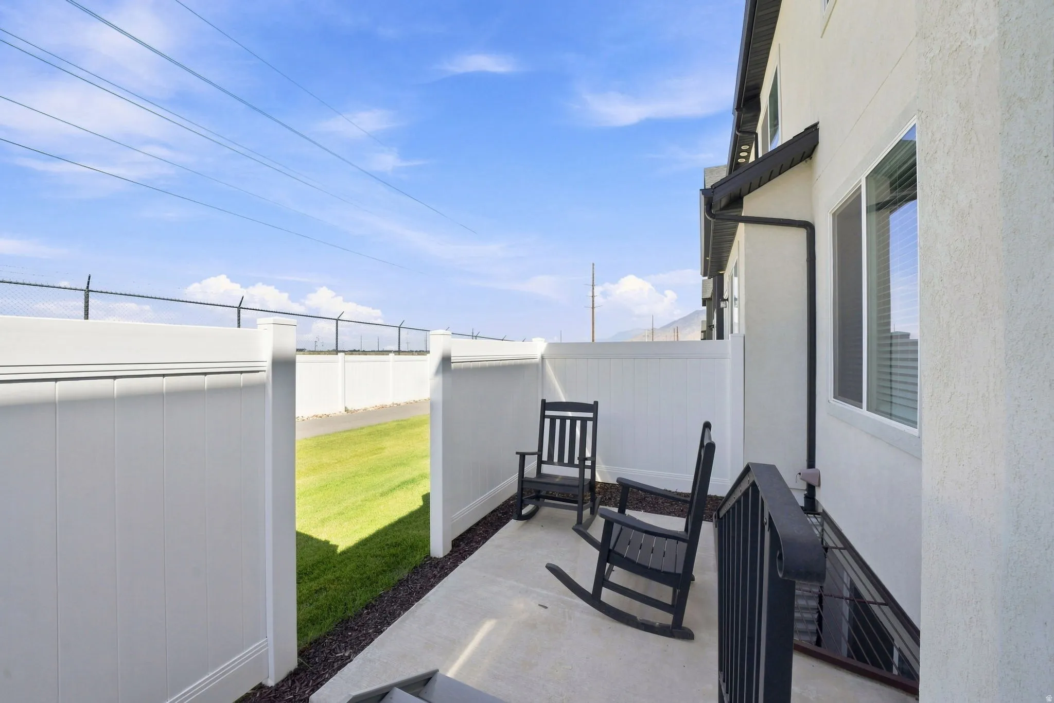 Outdoor patio with a concrete surface and white privacy fencing