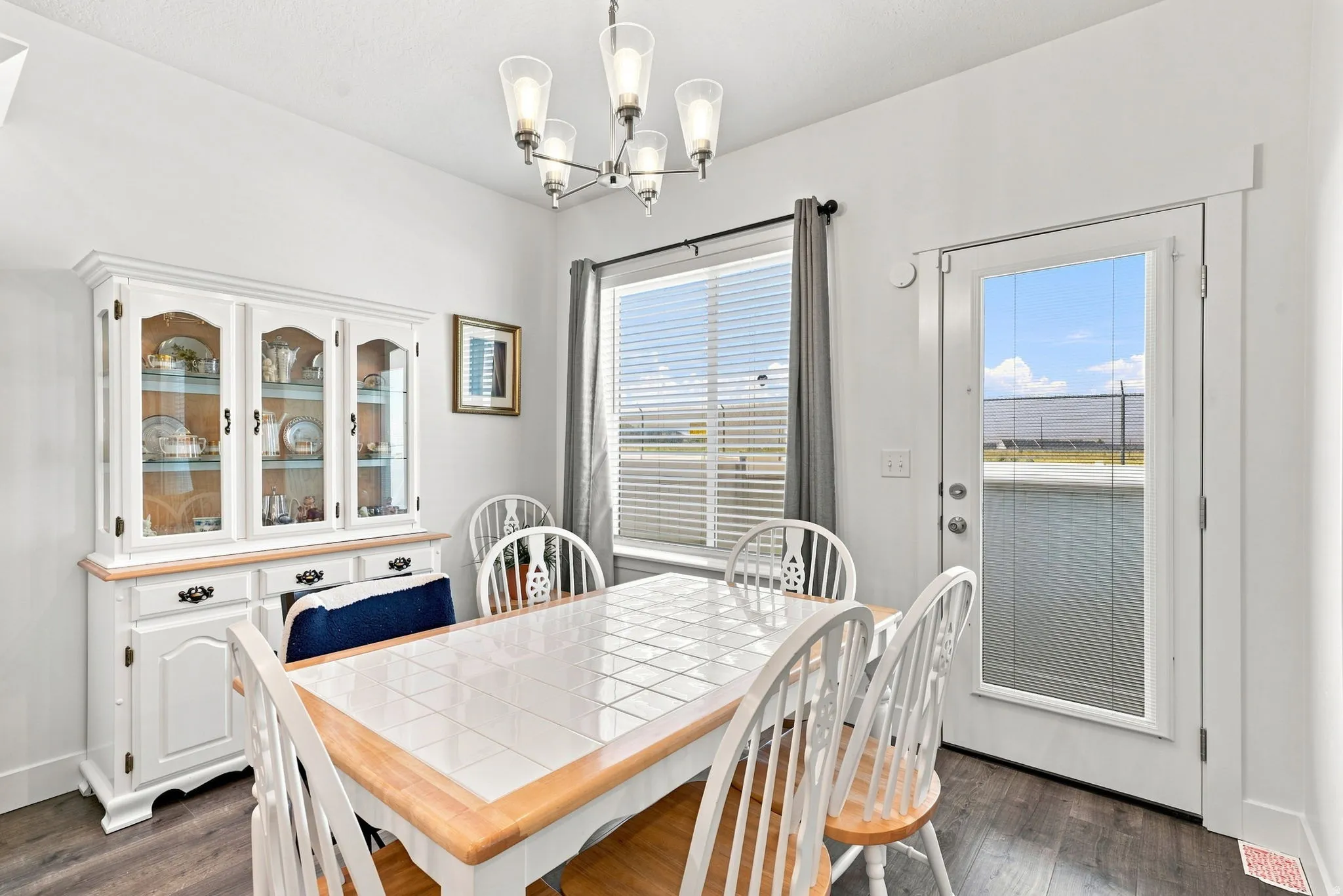 White interior walls, wood-finish flooring, built-in display cabinetry, ceiling-mounted light fixture, and a glass-paneled door