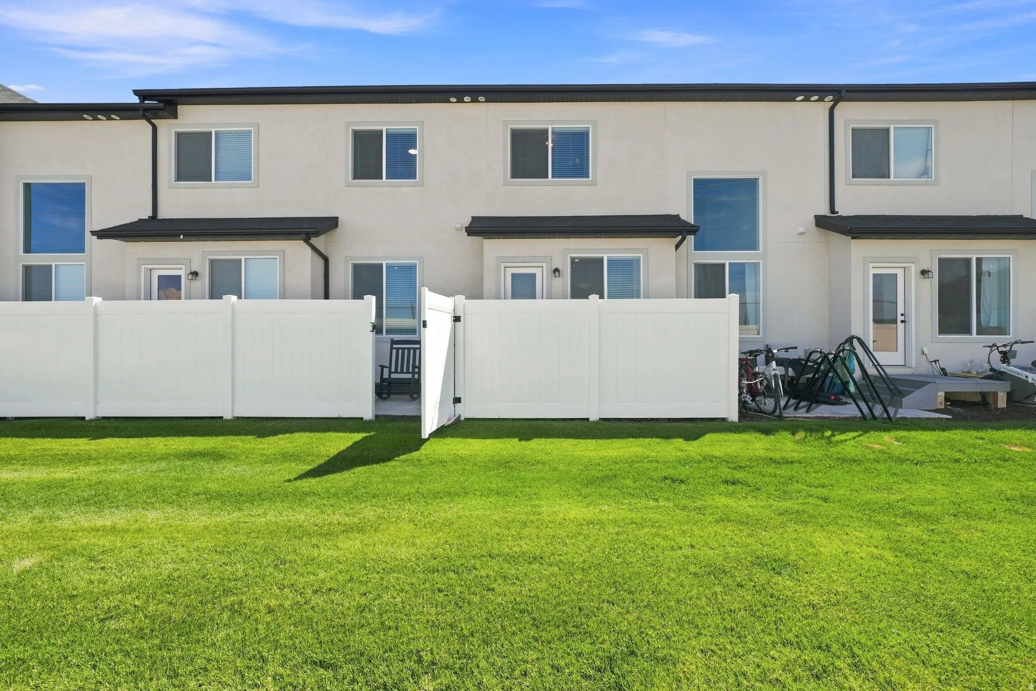 Expansive green lawn with a white vinyl fence and gate