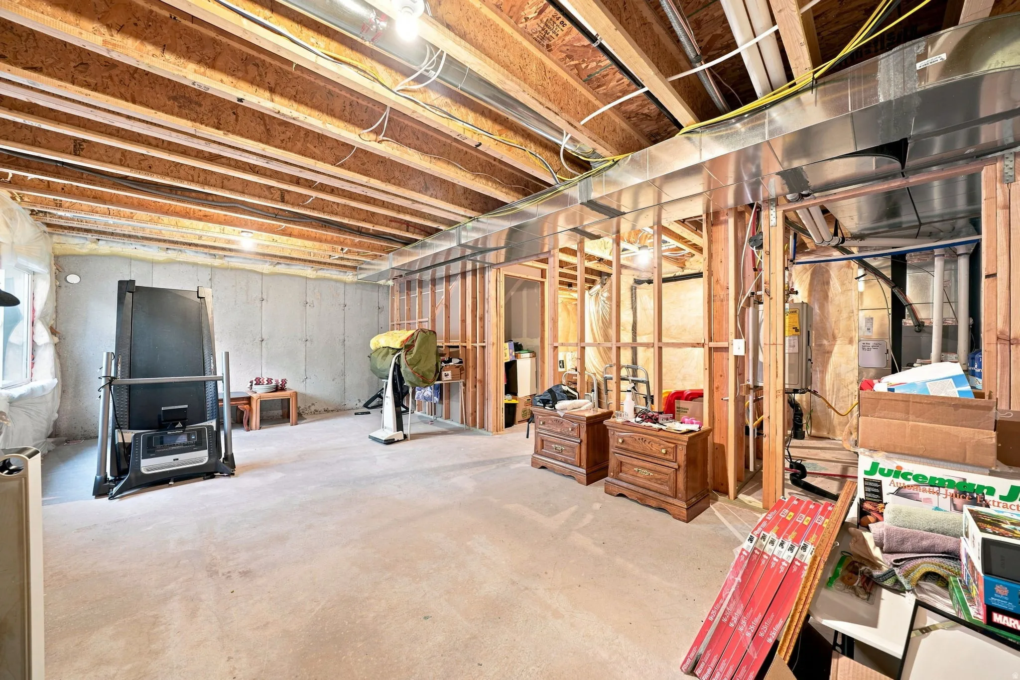 Unfinished basement with exposed beam ceiling, concrete flooring, and framed interior walls