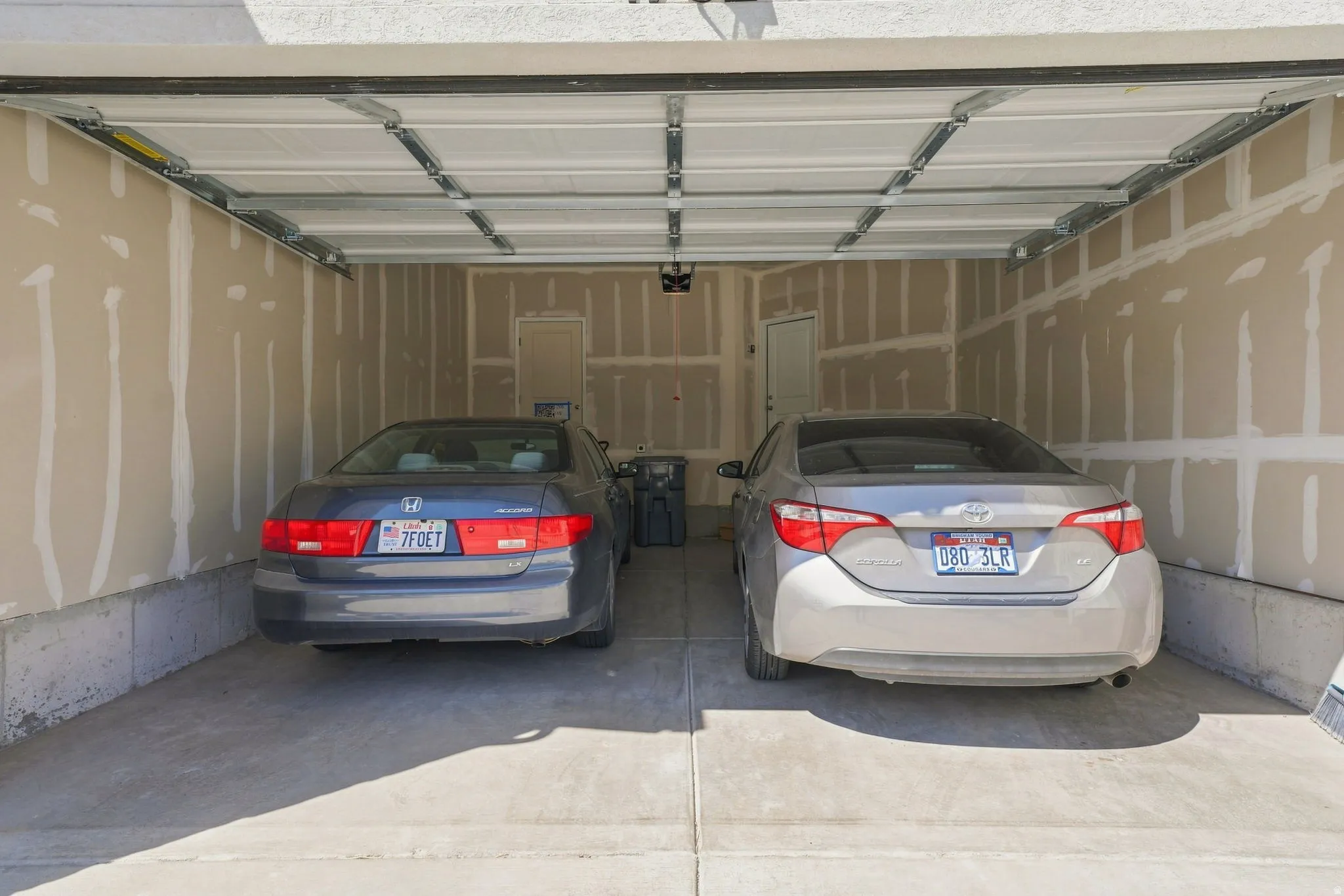 Two-car garage with a concrete floor, insulated garage door, and interior access door