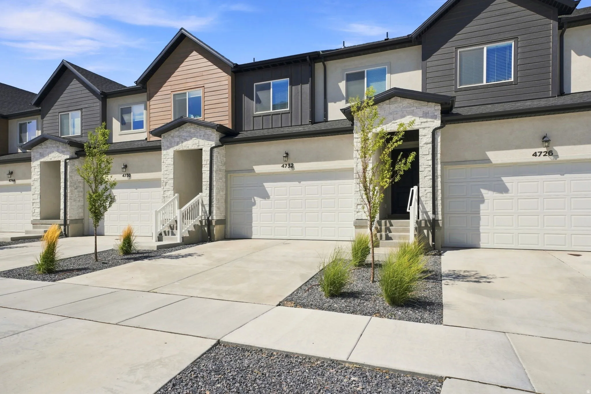 Modern townhome exterior with mixed material facade, stone accents, and a two-car garage