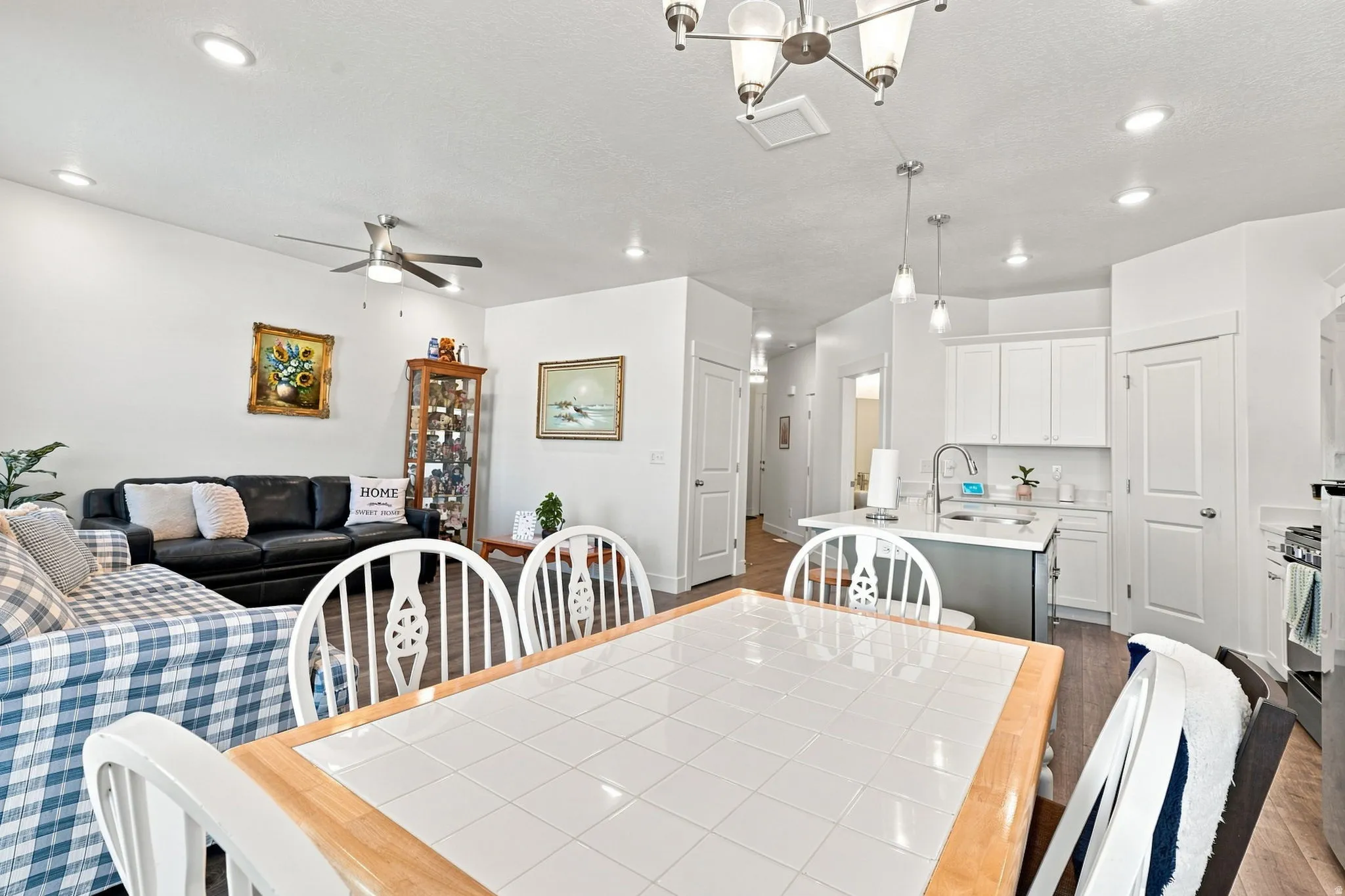 Open-concept living area featuring recessed lighting, a ceiling fan, wood-finish flooring, white cabinetry, and a kitchen island with pendant lighting