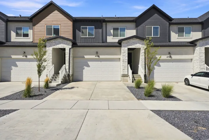 Contemporary townhome exterior featuring an attached garage, stone accents, and a covered entry