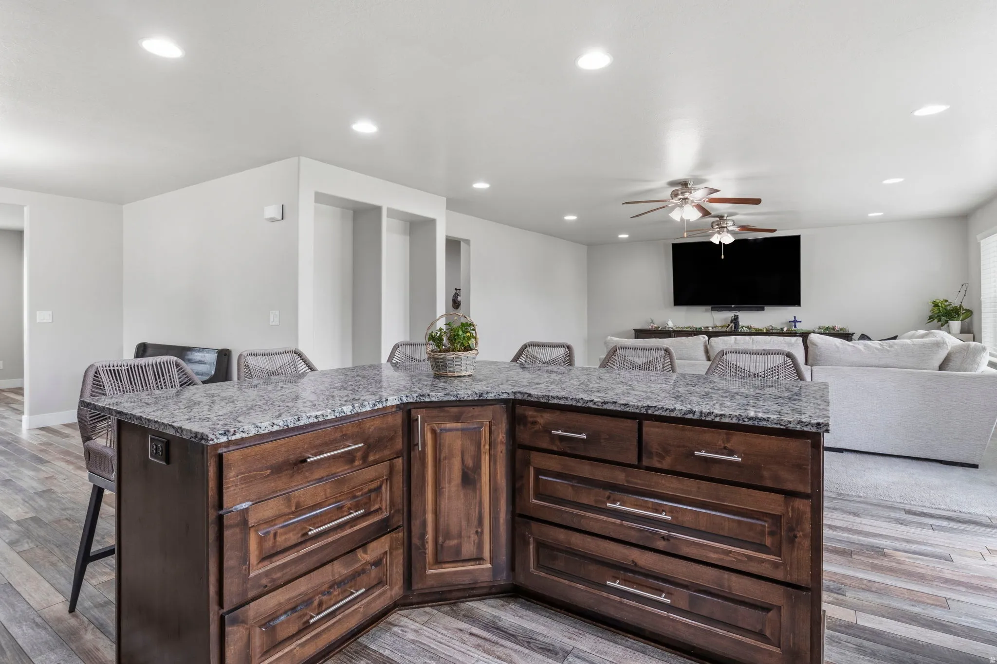 Kitchen island with a granite-style countertop, wood-finish cabinetry, and recessed lighting