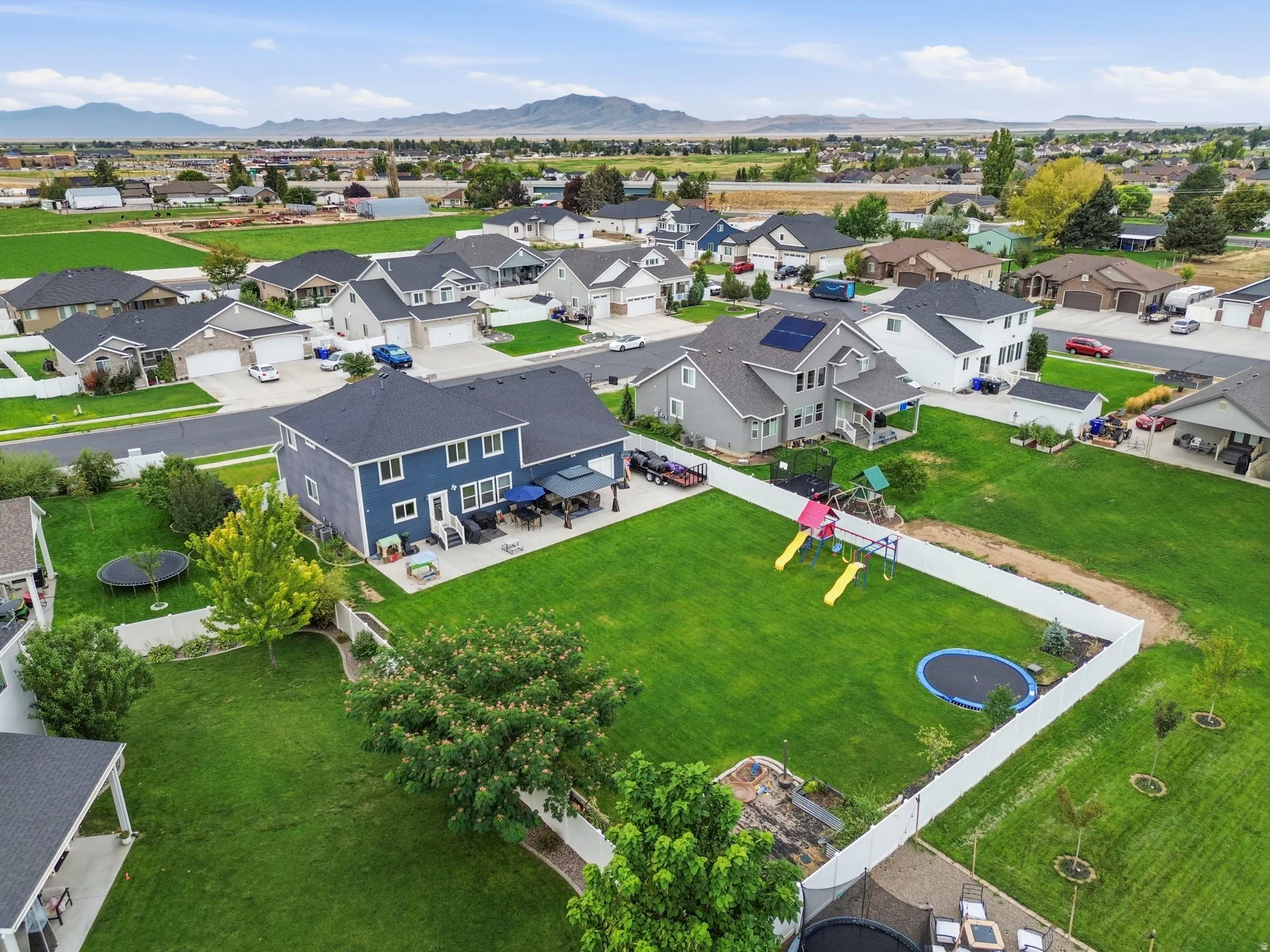 Expansive green lawn with a white privacy fence, offering clear mountain scenery