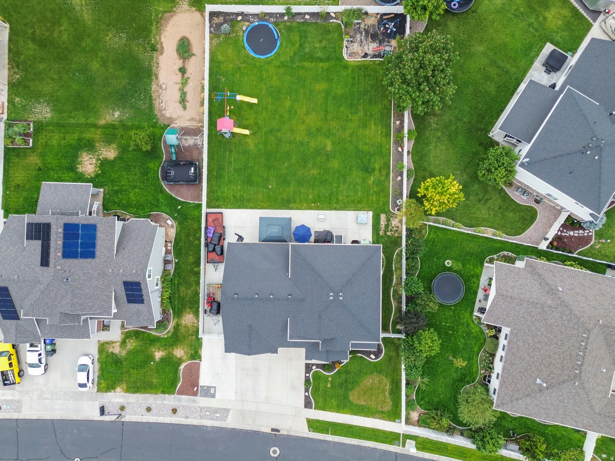Expansive backyard featuring a manicured lawn, concrete patio, and mature trees