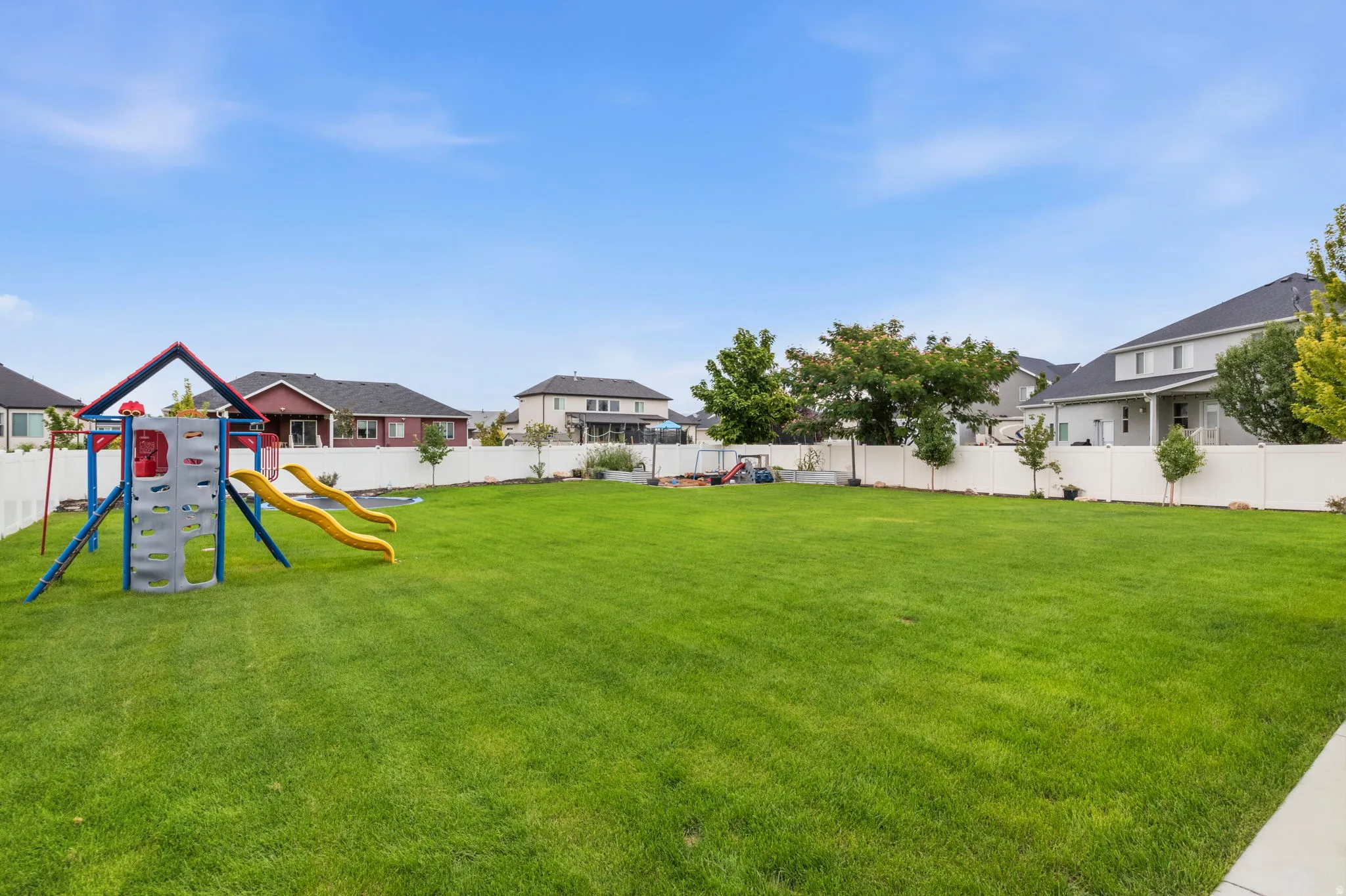 Expansive green lawn, white privacy fencing, and mature trees
