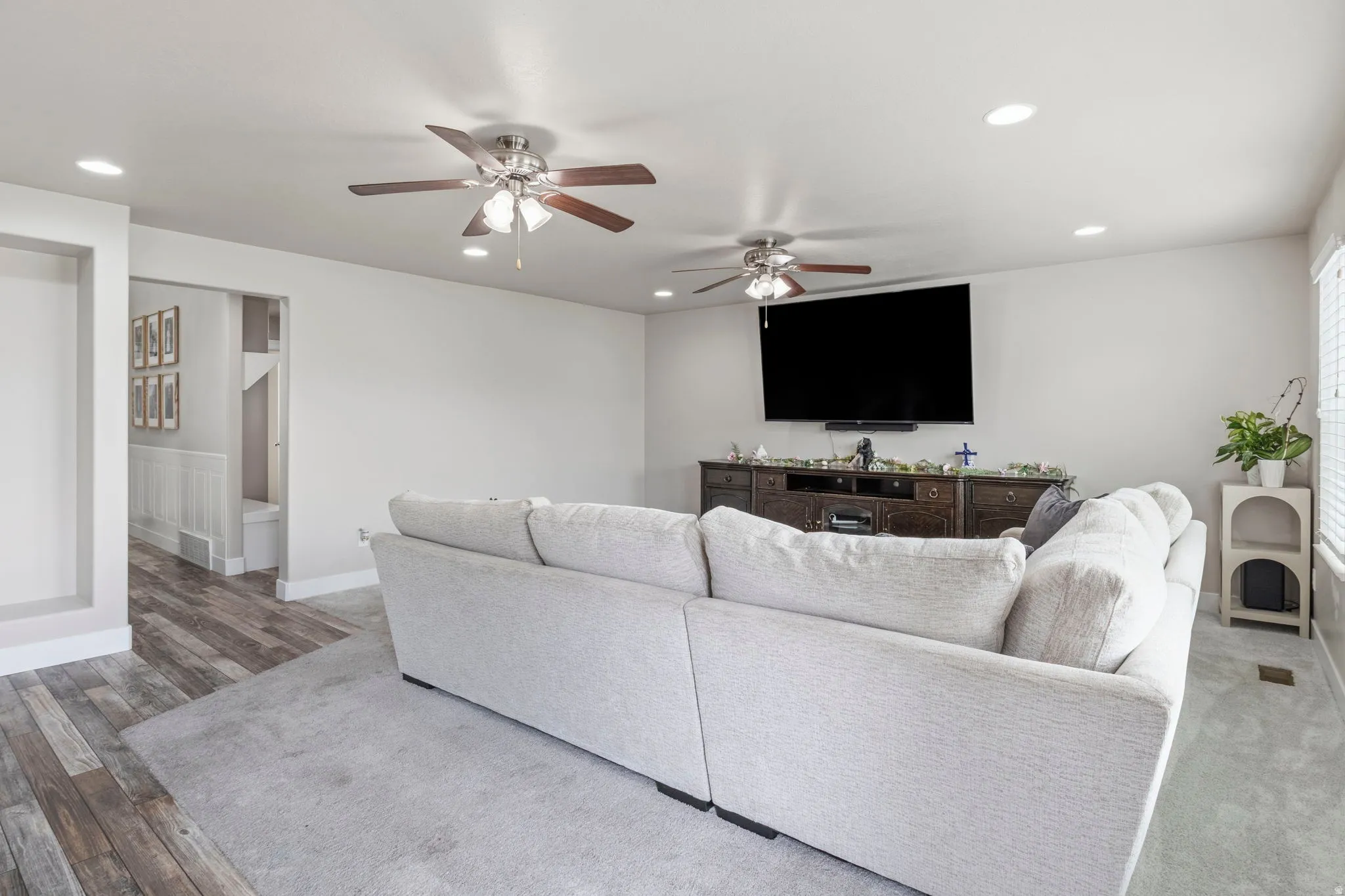 Recessed lighting with multiple ceiling fans and wood-finish flooring