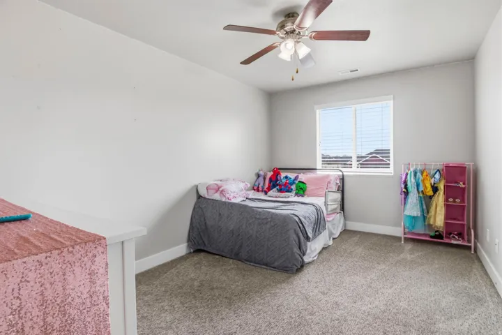Carpeted room with a ceiling fan, white walls, and a window with blinds