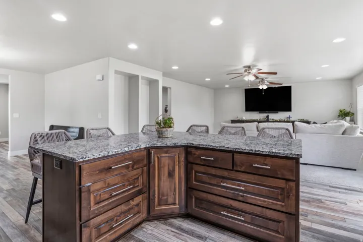 Kitchen island with a granite-style countertop, wood-finish cabinetry, and recessed lighting