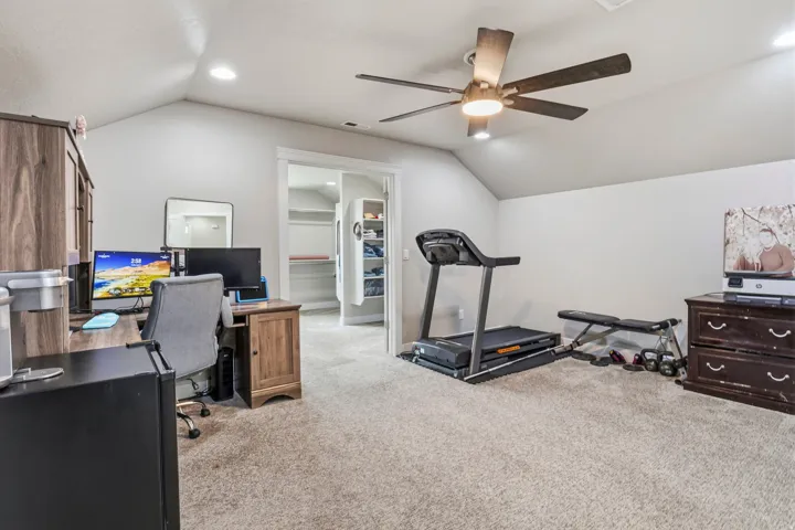 Carpeted room with vaulted ceilings and recessed lighting