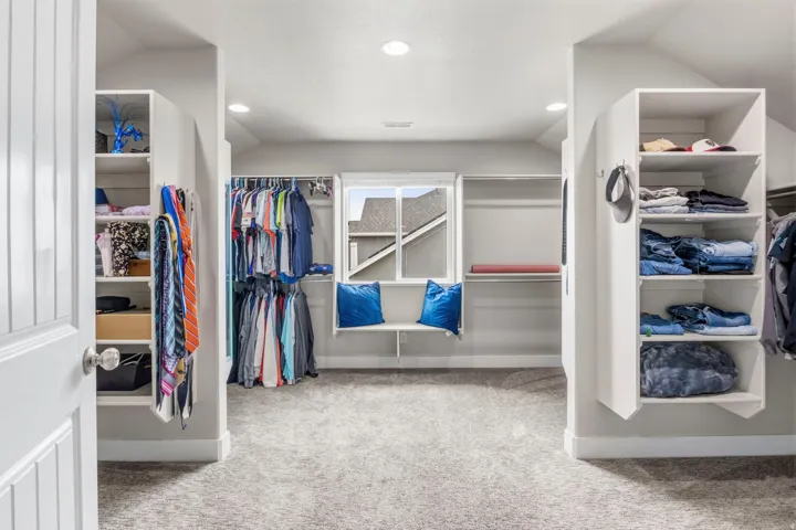 Expansive walk-in closet featuring built-in shelving, multiple hanging rods, a window, and recessed lighting