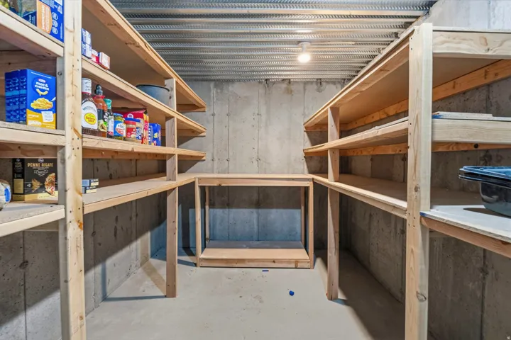 Concrete flooring with a built-in wooden shelving system, accompanied by a corrugated metal ceiling