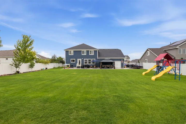 Expansive lawn area with a multi-level home featuring blue siding and white trim