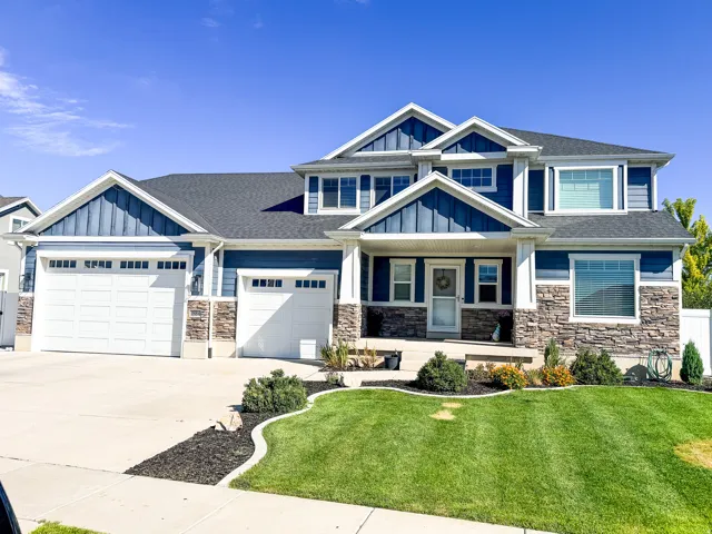 Exterior featuring blue siding, stone facade accents, multiple gables, a two-car garage, and a single-car garage