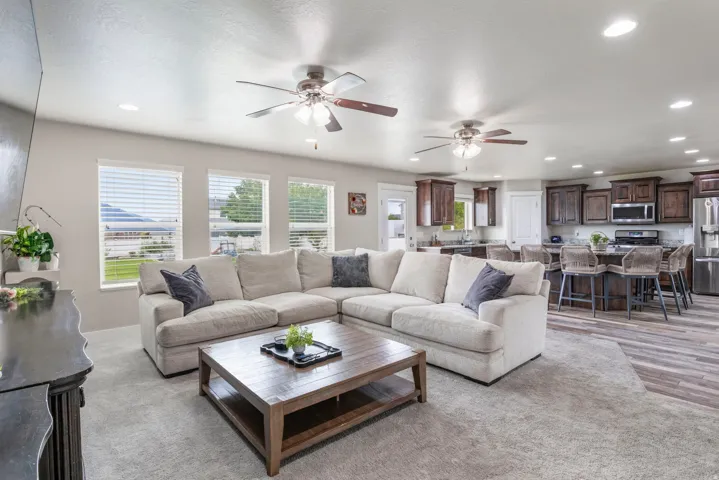 Recessed lighting, multiple windows with blinds, ceiling fans, wood-finish flooring, and dark wood cabinetry