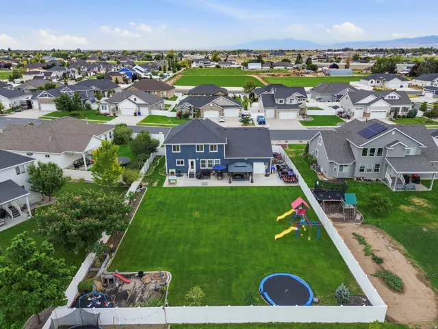 Expansive backyard with a manicured lawn, white vinyl fencing, and a concrete patio