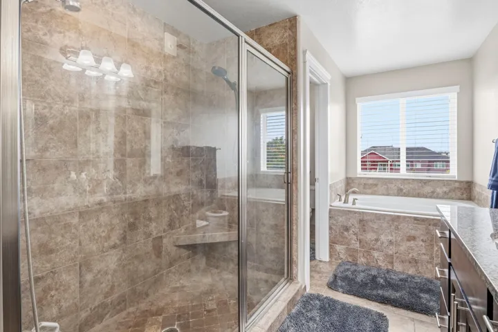 Glass-enclosed shower with tiled walls and a built-in bench