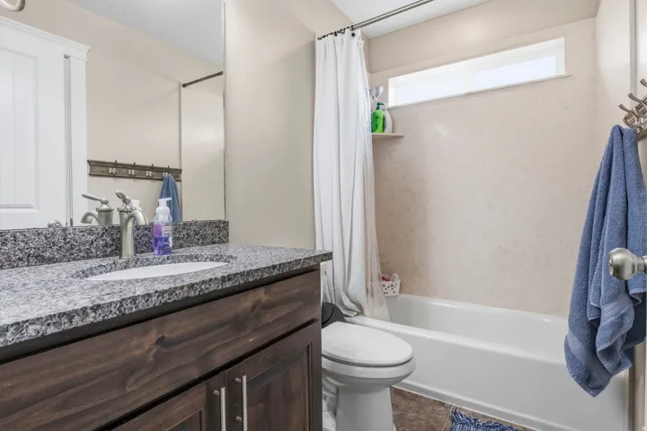 Wood-finish vanity with a built-in sink, granite countertop, and brushed nickel faucet